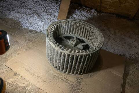 Blower wheel pulled from an air handler, the vanes packed with gray dust