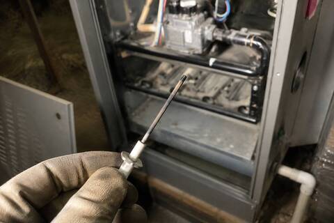 Flame sensor rod out of a furnace, held in a gloved hand