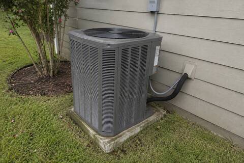 Outdoor unit against a Hardie-siding wall with the line set entering through the siding