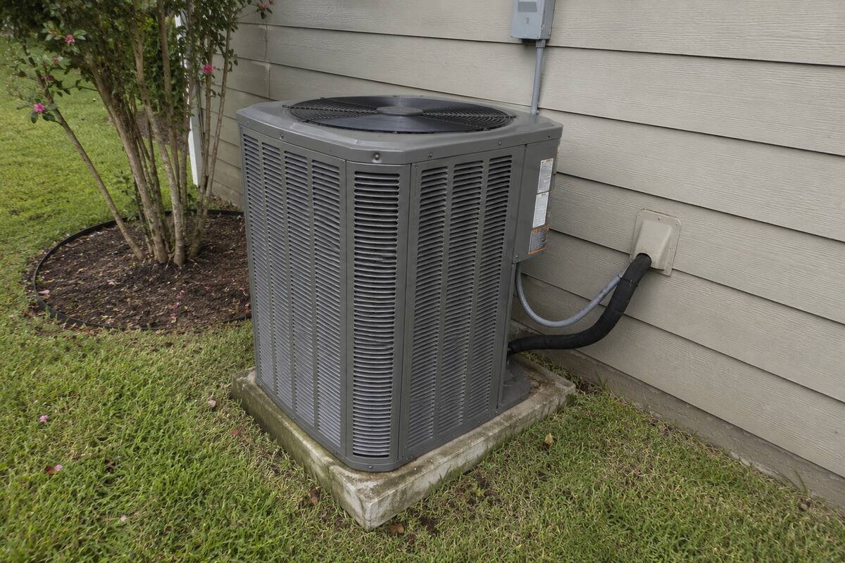 Outdoor unit against a Hardie-siding wall with the line set entering through the siding